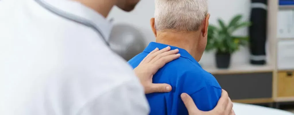 Doctor reassuring a patient with a hand on his shoulder in a clinic office