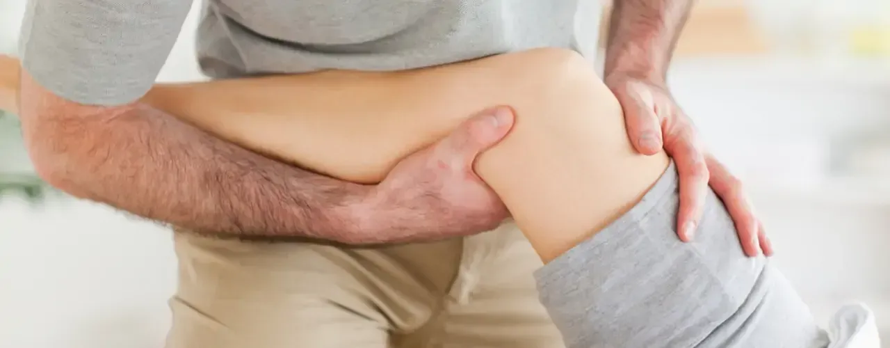 Person holding another person’s bent knee during a leg stretch or massage
