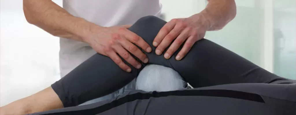 Massage therapist stretching a person’s legs on a treatment table