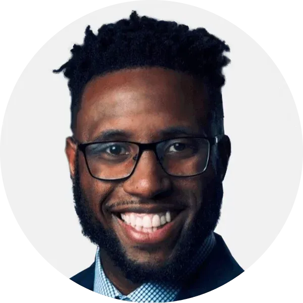 Smiling man with glasses and beard in a dark suit on a light background