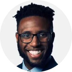 Smiling man with glasses and a beard against a light gray background