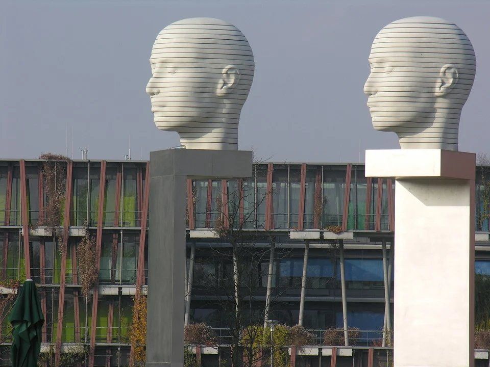 pixabay, lizenzfrei Zwei Skulpturen von Köpfen stehen nebeneinander vor einem Gebäude