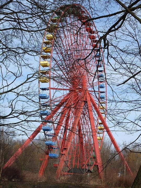 pixabay, lizenzfrei Ein rot-blaues Riesenrad ist von Bäumen umgeben.