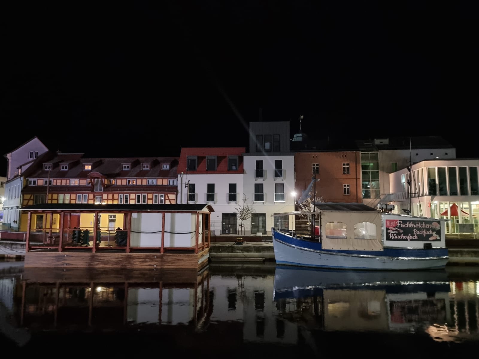 eigene Aufnahme 2021 Vor einer Häuserzeile liegt nachts ein Boot vor Anker.