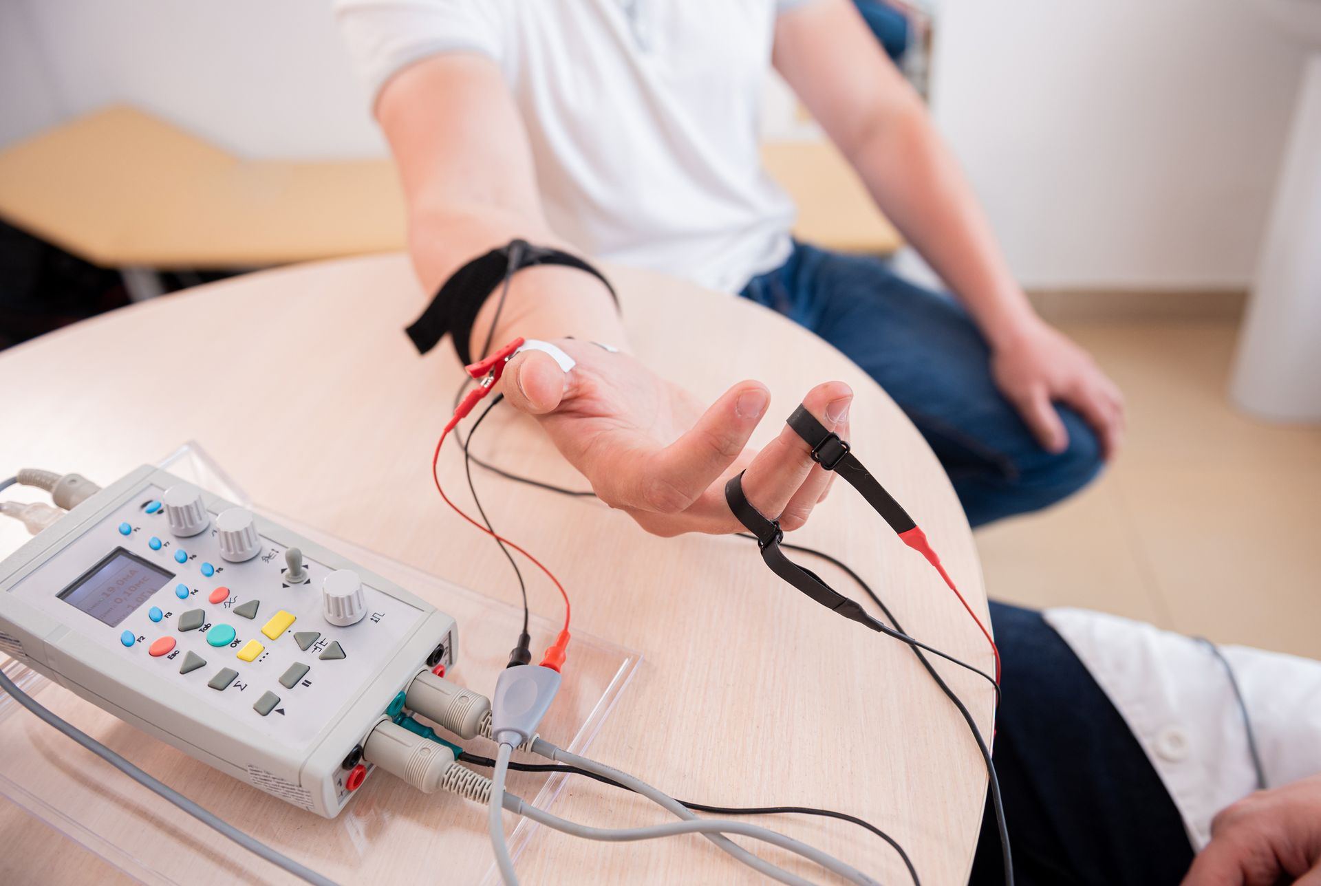 A person is sitting at a table with a device on their hand.