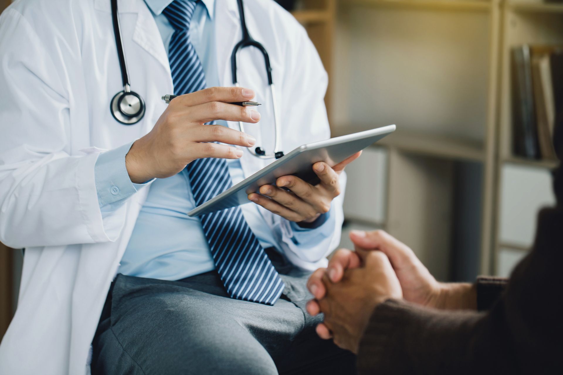 A doctor is talking to a patient while holding a tablet.