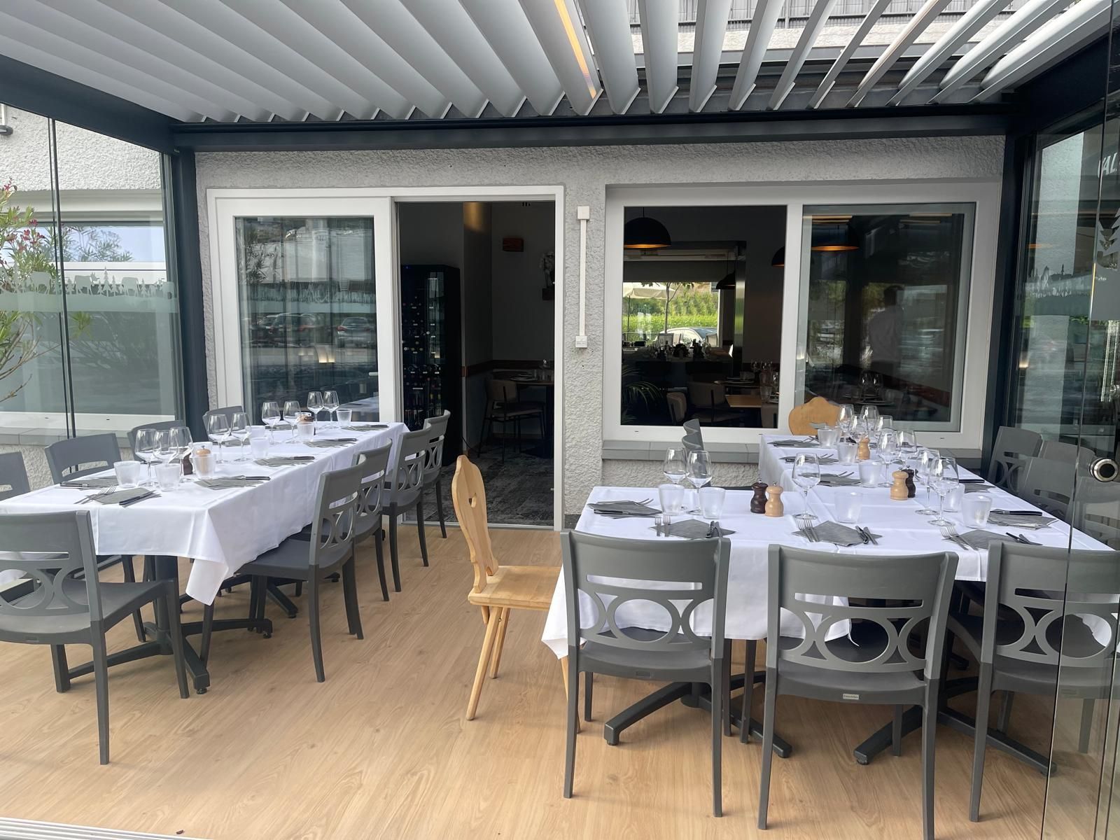 Un restaurant avec des tables et des chaises installées à l'extérieur sous une pergola.