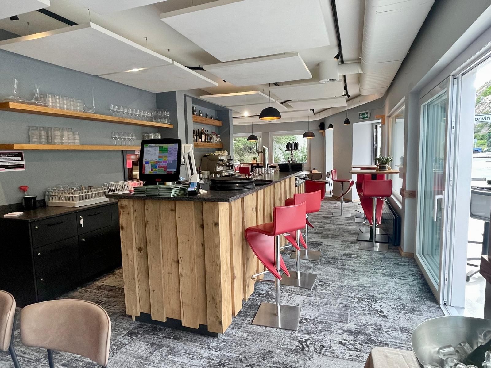 Un restaurant avec un bar en bois et des chaises rouges.