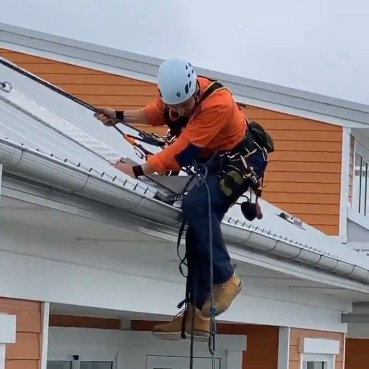 A Man Is Working On The Roof Of A Building — Freshwater Exterior Cleaning in Lennox Head, NSW