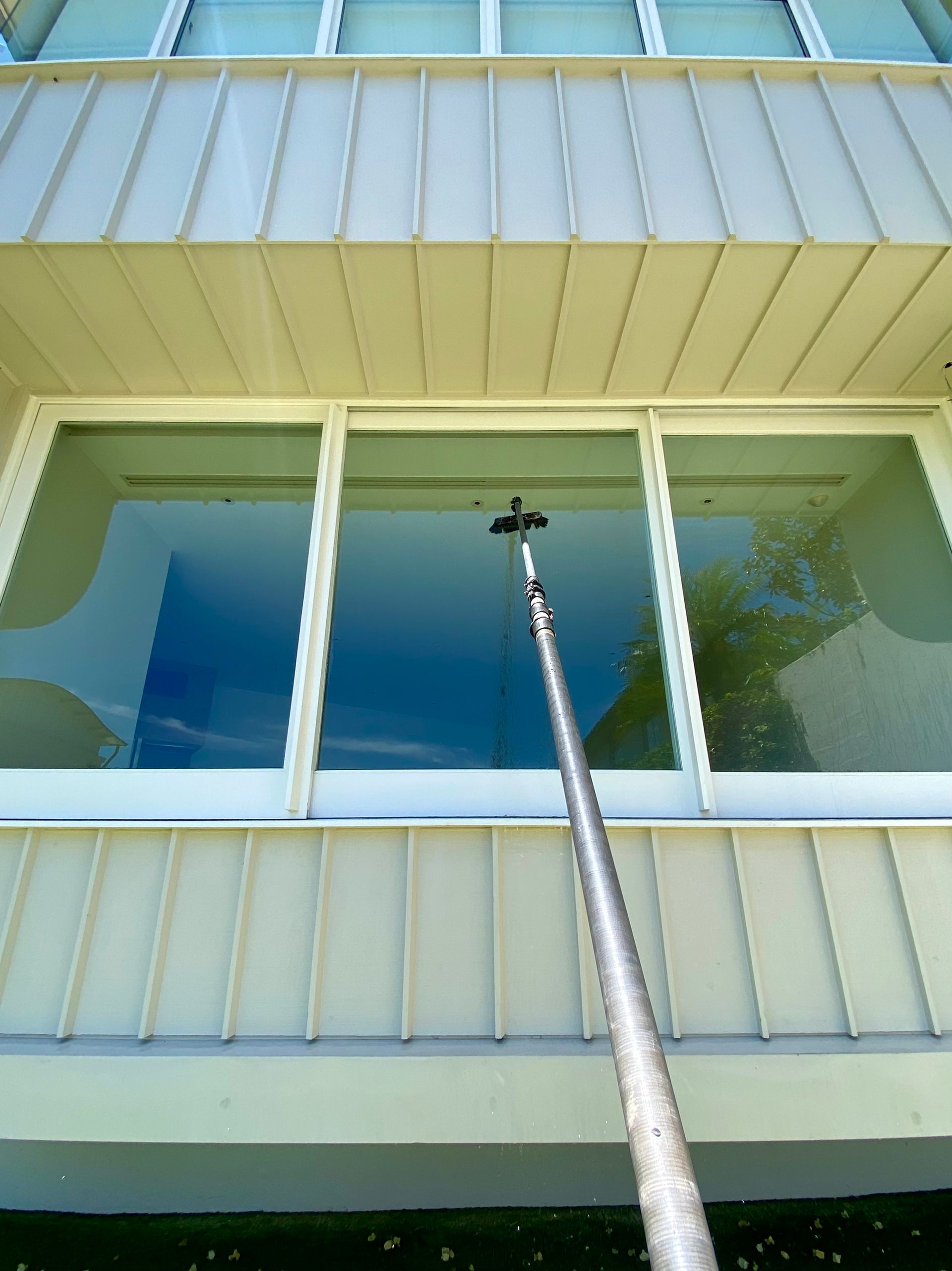 A Person Is Cleaning The Side Of A Building With A Brush — Freshwater Exterior Cleaning in Ballina, NSW