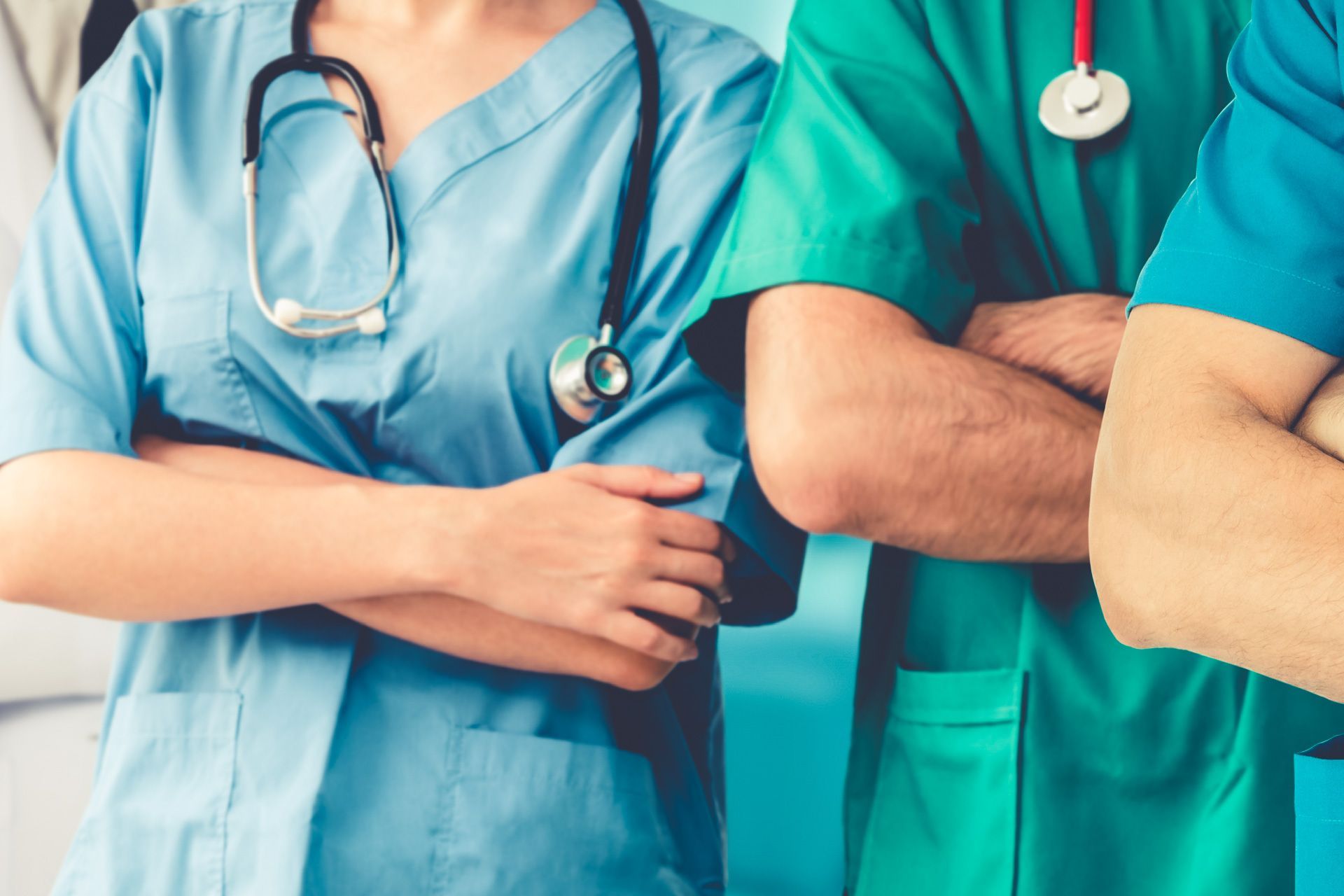 Un grupo de médicos y enfermeras están de pie uno al lado del otro con los brazos cruzados.