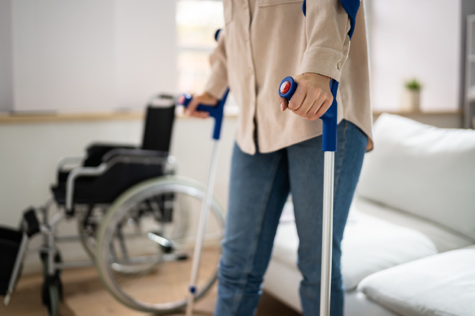 Una mujer con muletas está parada frente a una silla de ruedas.