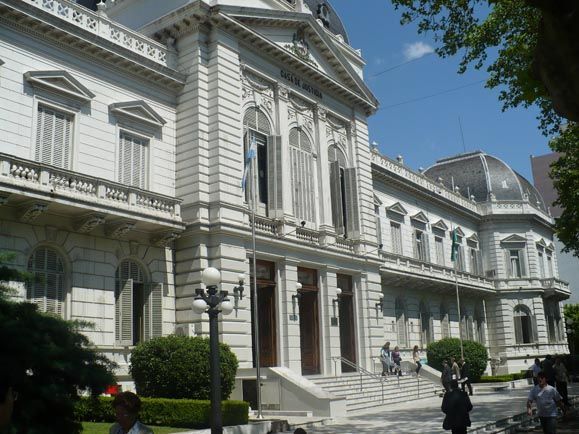 Un gran edificio blanco con gente parada frente a él.