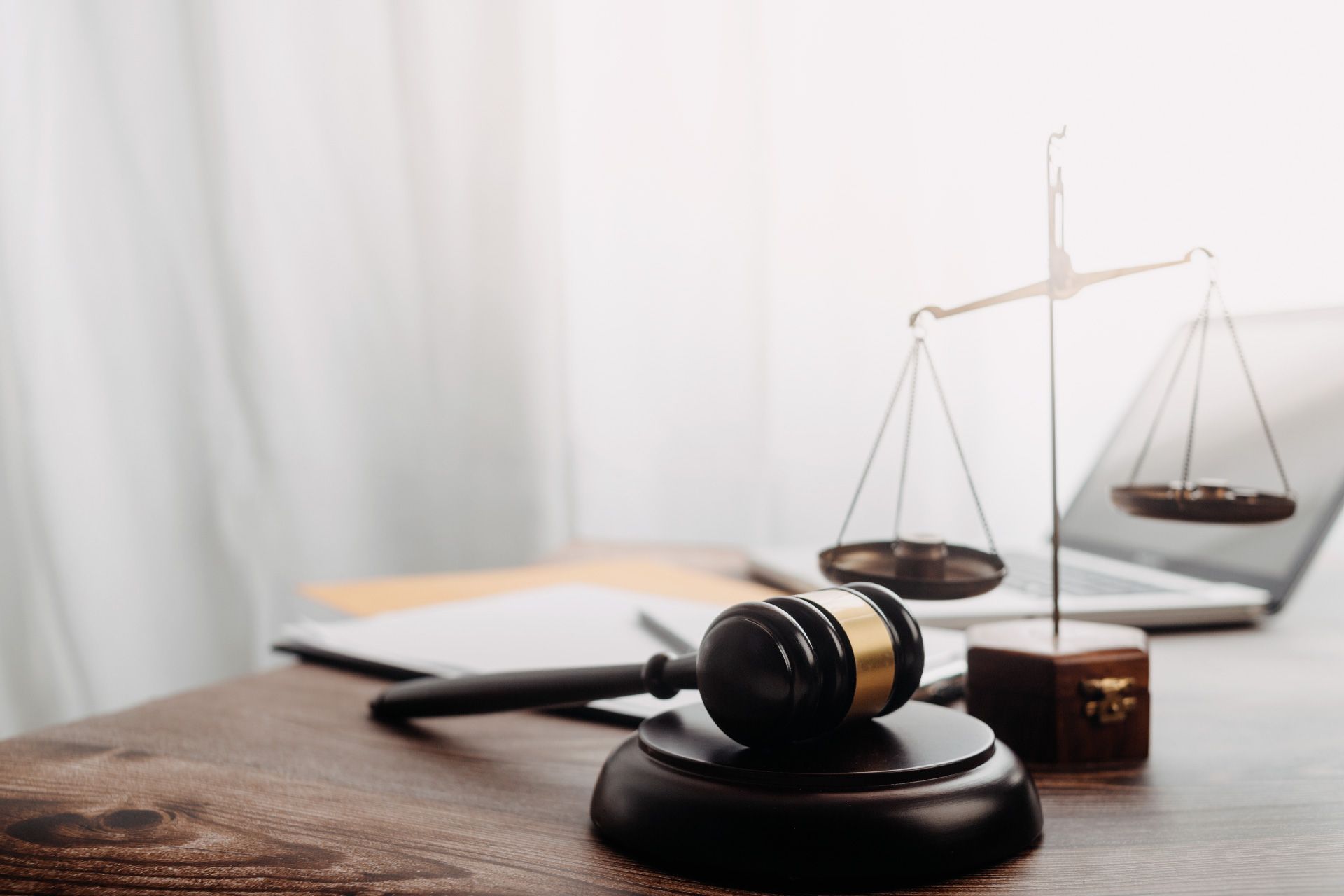El mazo de un juez y la balanza de la justicia están sobre una mesa de madera.