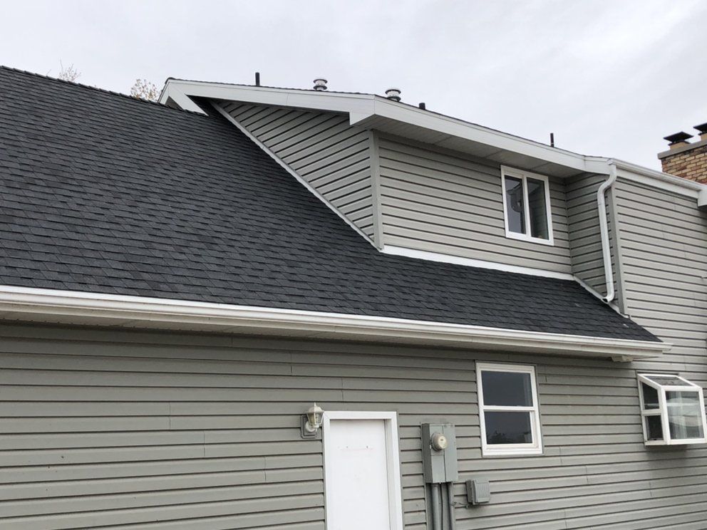 A house with a gray siding and a black roof.