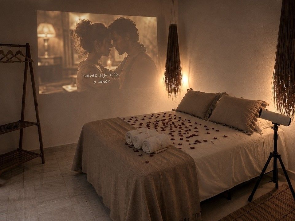 Quarto aconchegante com cama arrumada, iluminação quente, decoração pendurada e um filme projetado na parede.