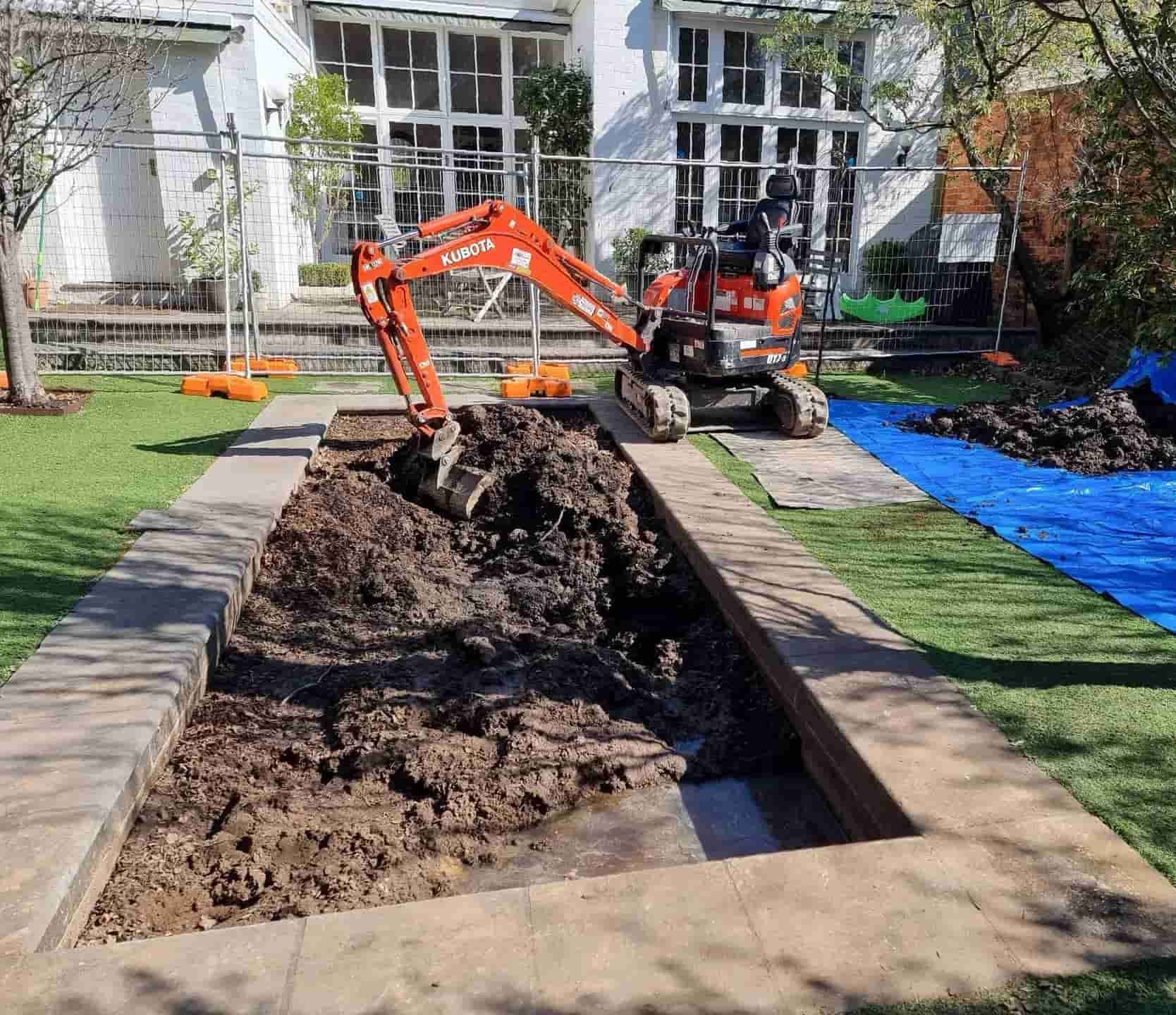 An Orange Mini Excavator Digging in a Rectangular Patch of Dirt Framed — All Over Pool Removals in Glen Waverley, VIC