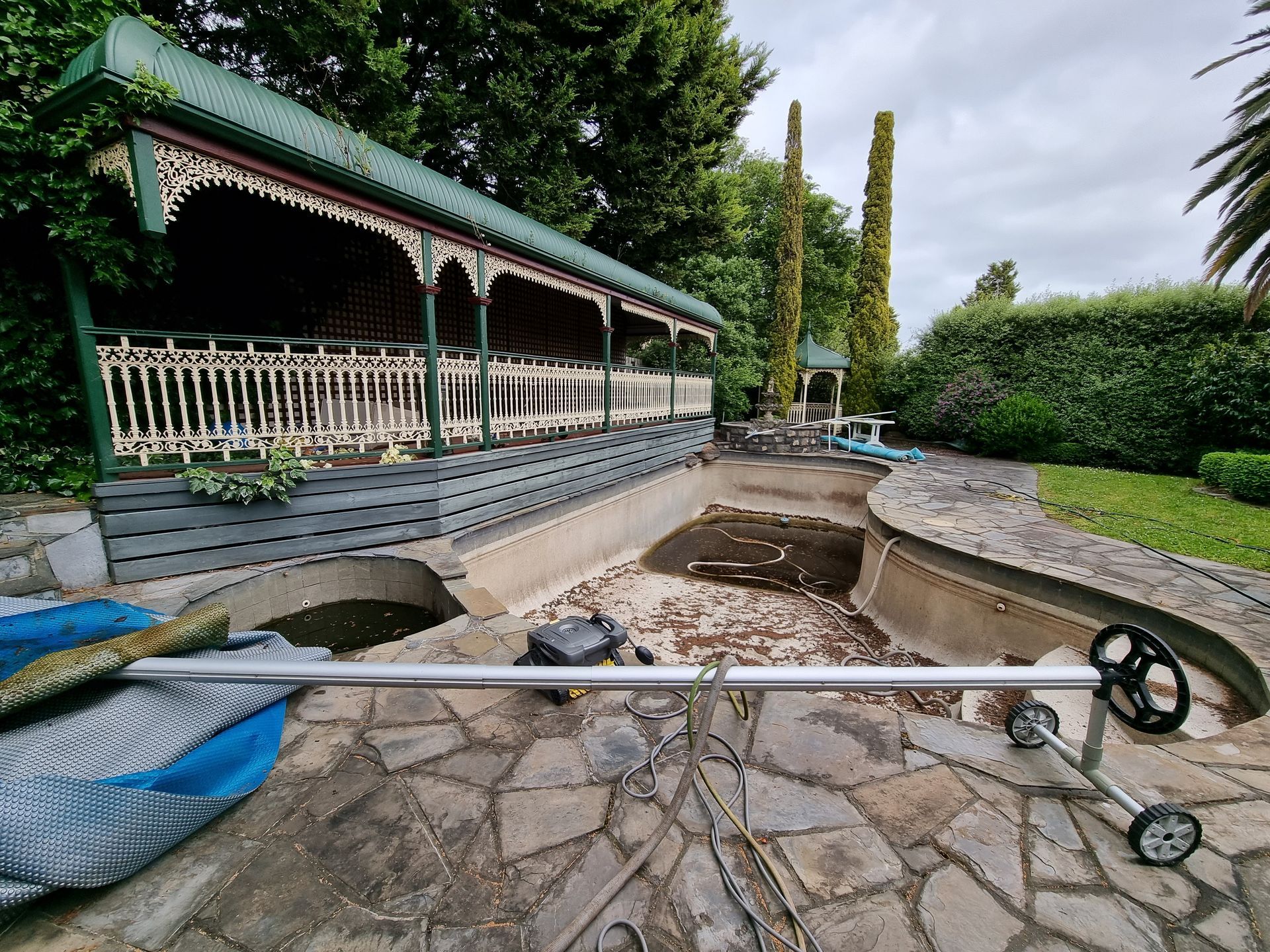 A Dry Backyard Swimming Pool With a Covered Patio Area in the Background — All Over Pool Removals in Chadstone, VIC