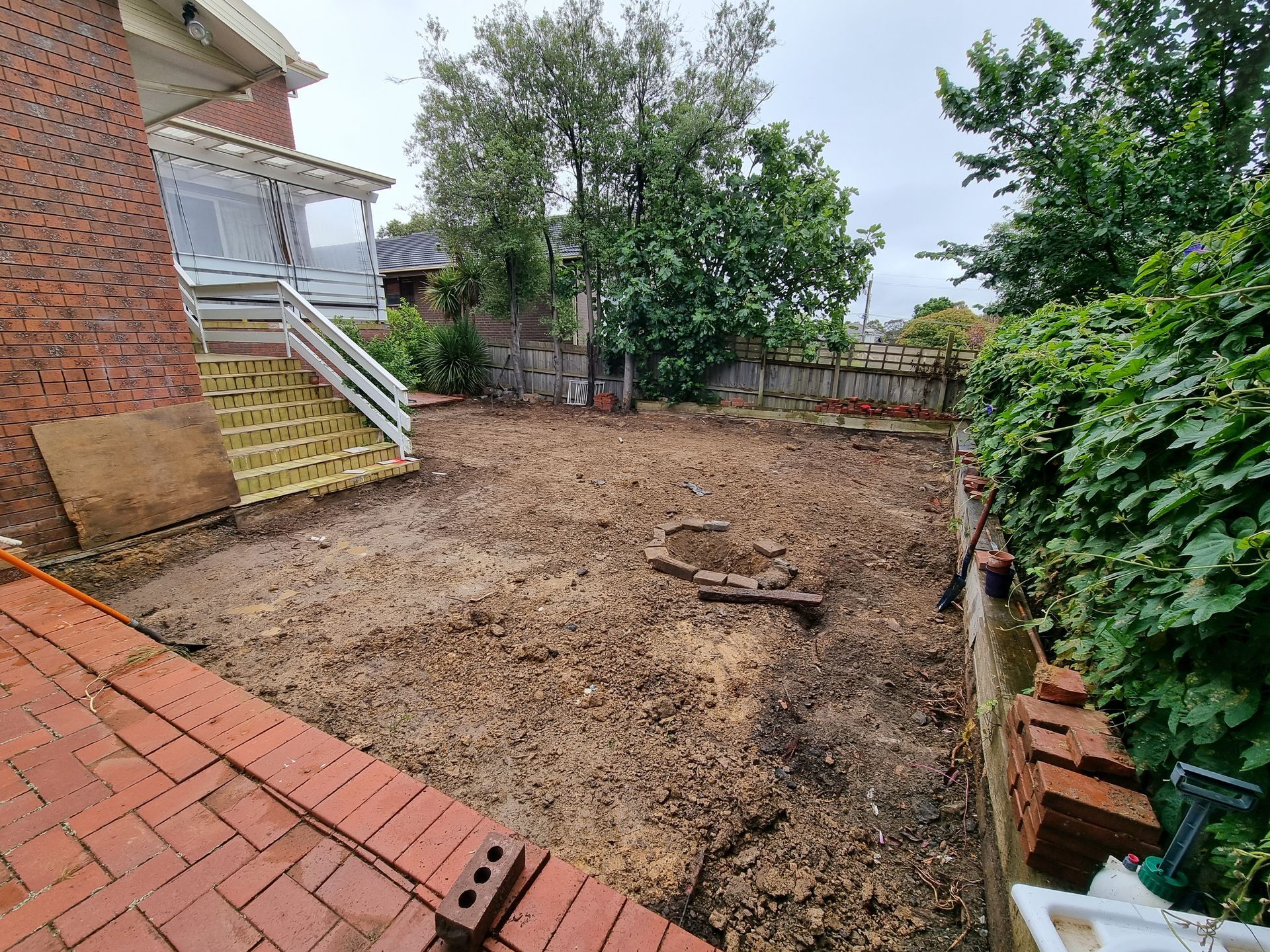 A Backyard With Bare Earth, a Brick Patio, Yellow Stairs Leading to a Porch — All Over Pool Removals in Templestowe, VIC