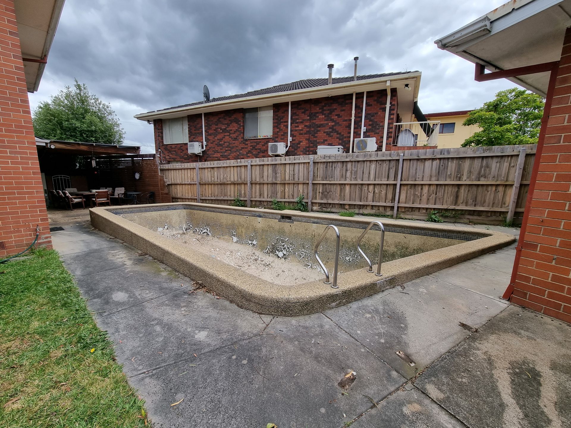 An Empty, Weathered Backyard Swimming Pool With a Textured Border — All Over Pool Removals in Surrey Hills, VIC