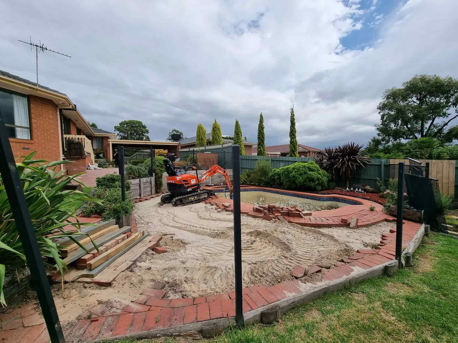 An Orange Excavator Sits in a Backyard Undergoing Construction — All Over Pool Removals in Lilydale, VIC