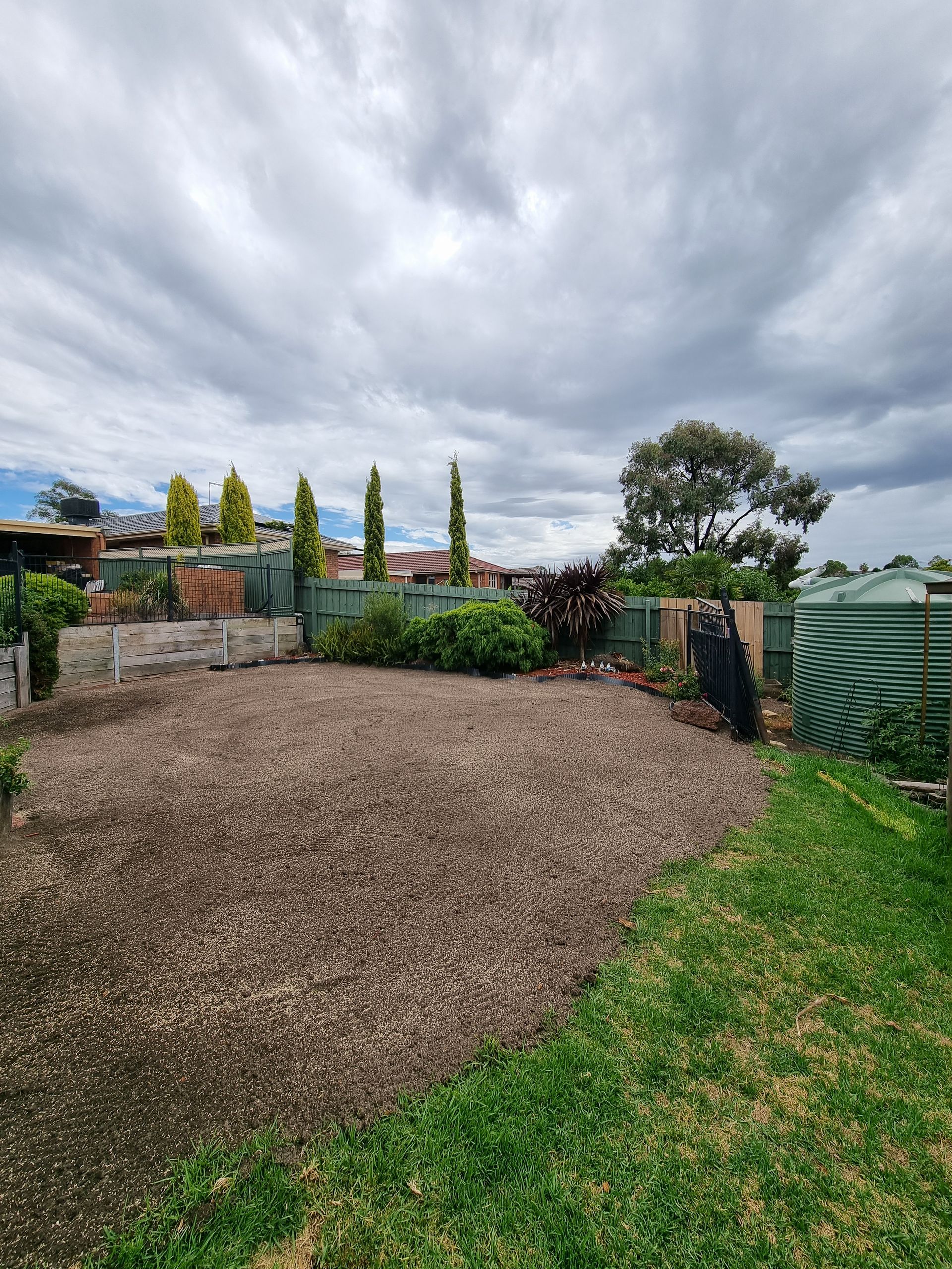A Backyard With a Large Gravel Area Bordered by Grass, a Fence — All Over Pool Removals in Templestowe, VIC