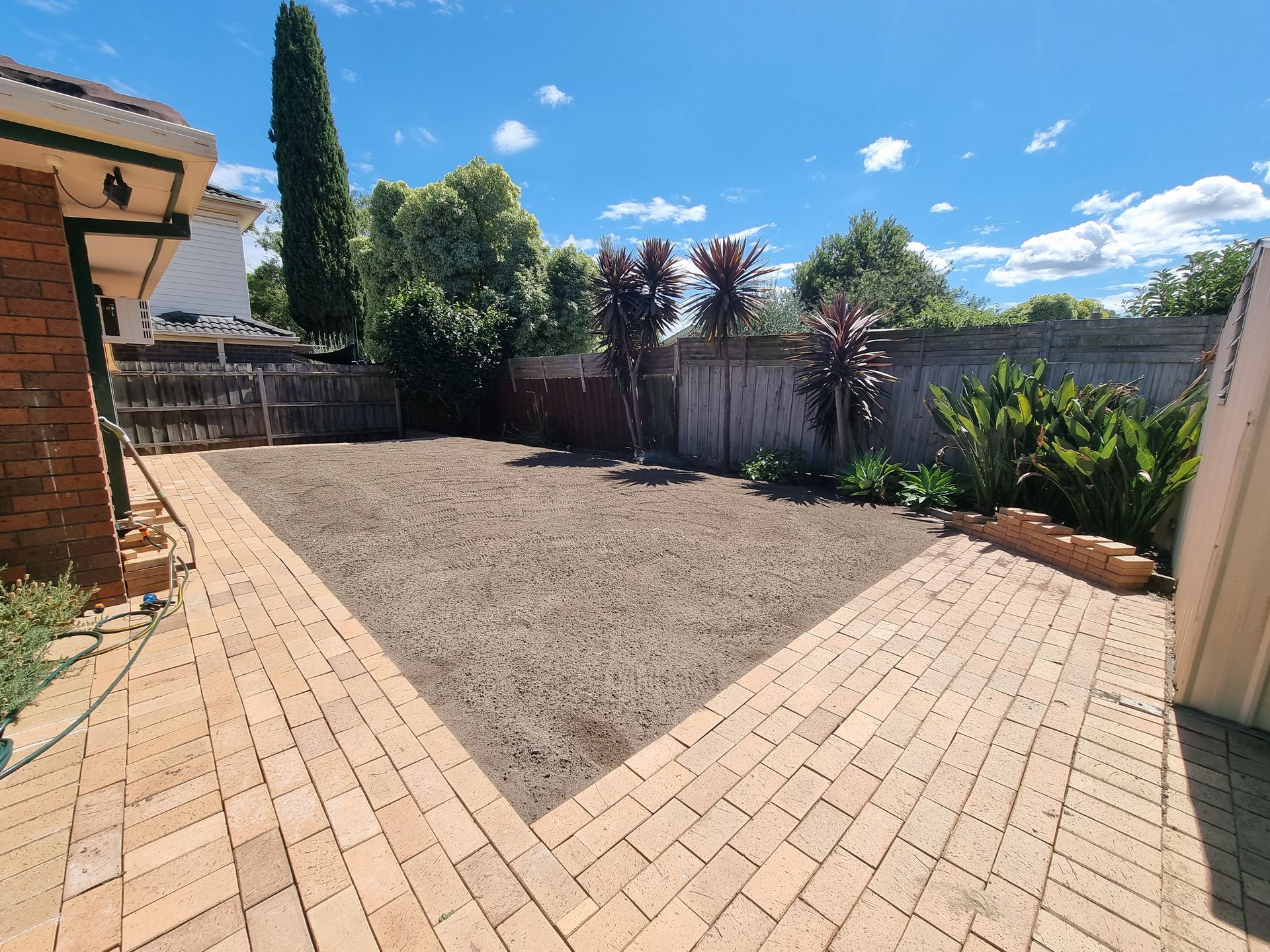 A Backyard With a Central Gravel Area Framed by Light Brown Brick Pavers — All Over Pool Removals in Surrey Hills, VIC