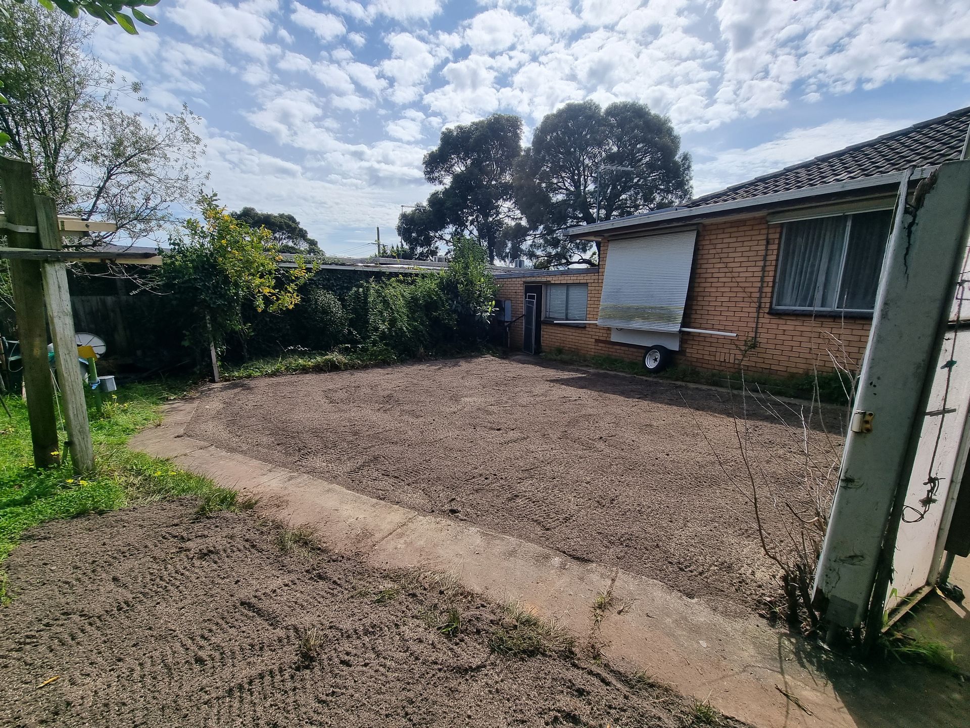 A Backyard With a Large, Gravel-covered Area, a Paved Path, and a Brick House — All Over Pool Removals in Upwey, VIC