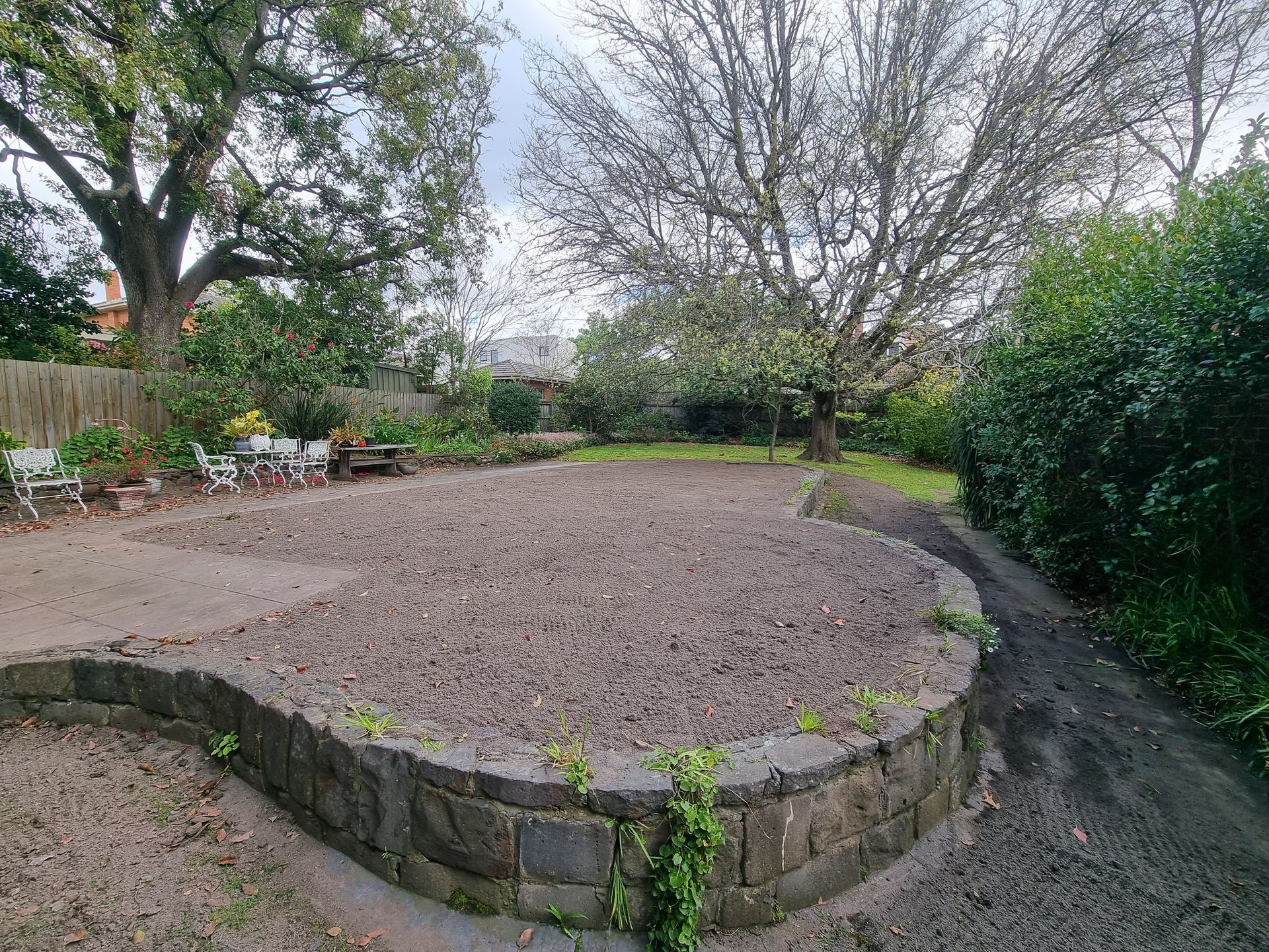 A Landscaped Backyard Features a Raised, Curved Stone Planter Bed Filled — All Over Pool Removals in Glen Waverley, VIC