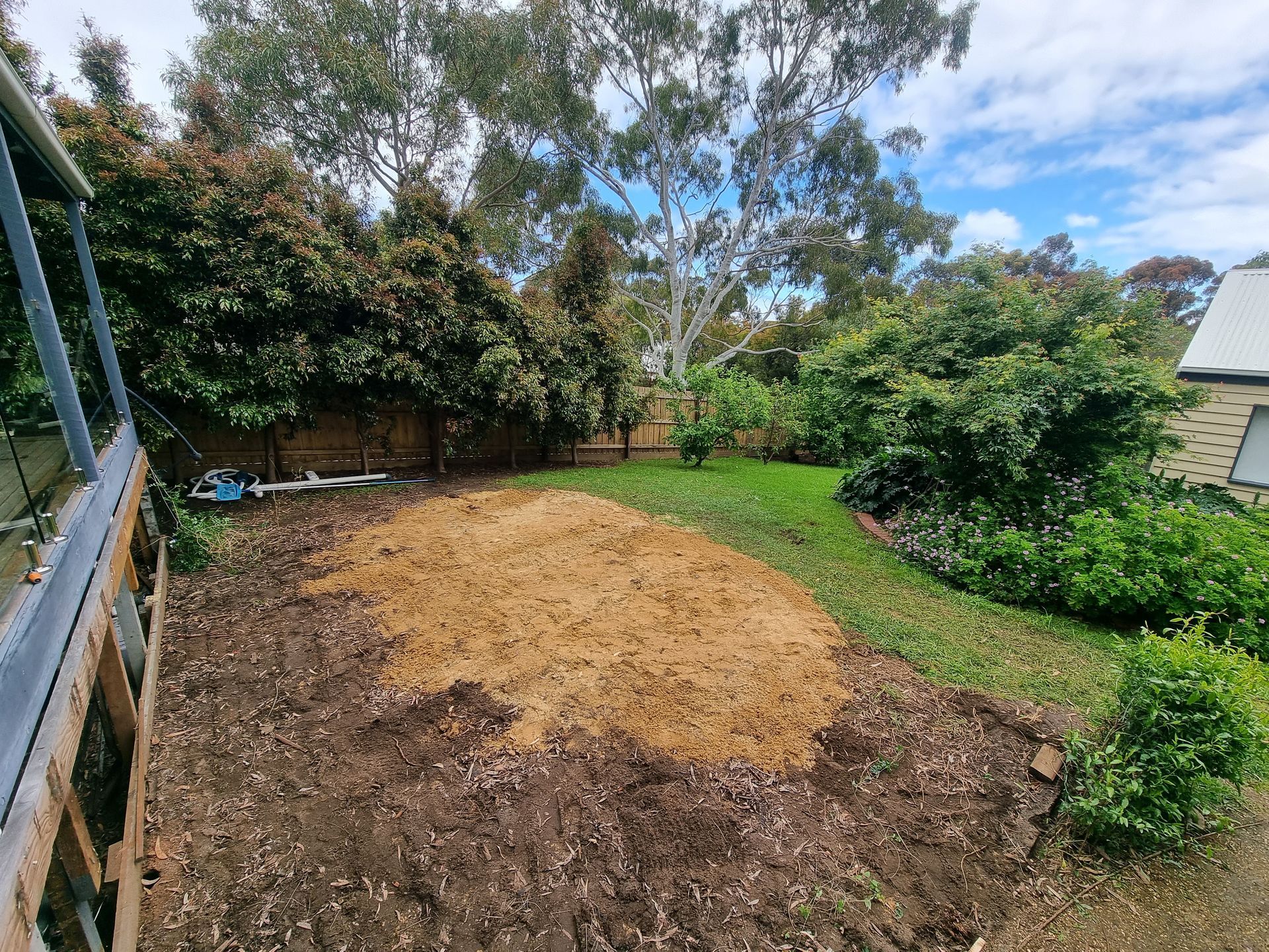 A Patch of Bare Brown Dirt Sits in a Green Backyard With Lush Trees — All Over Pool Removals in Templestowe, VIC