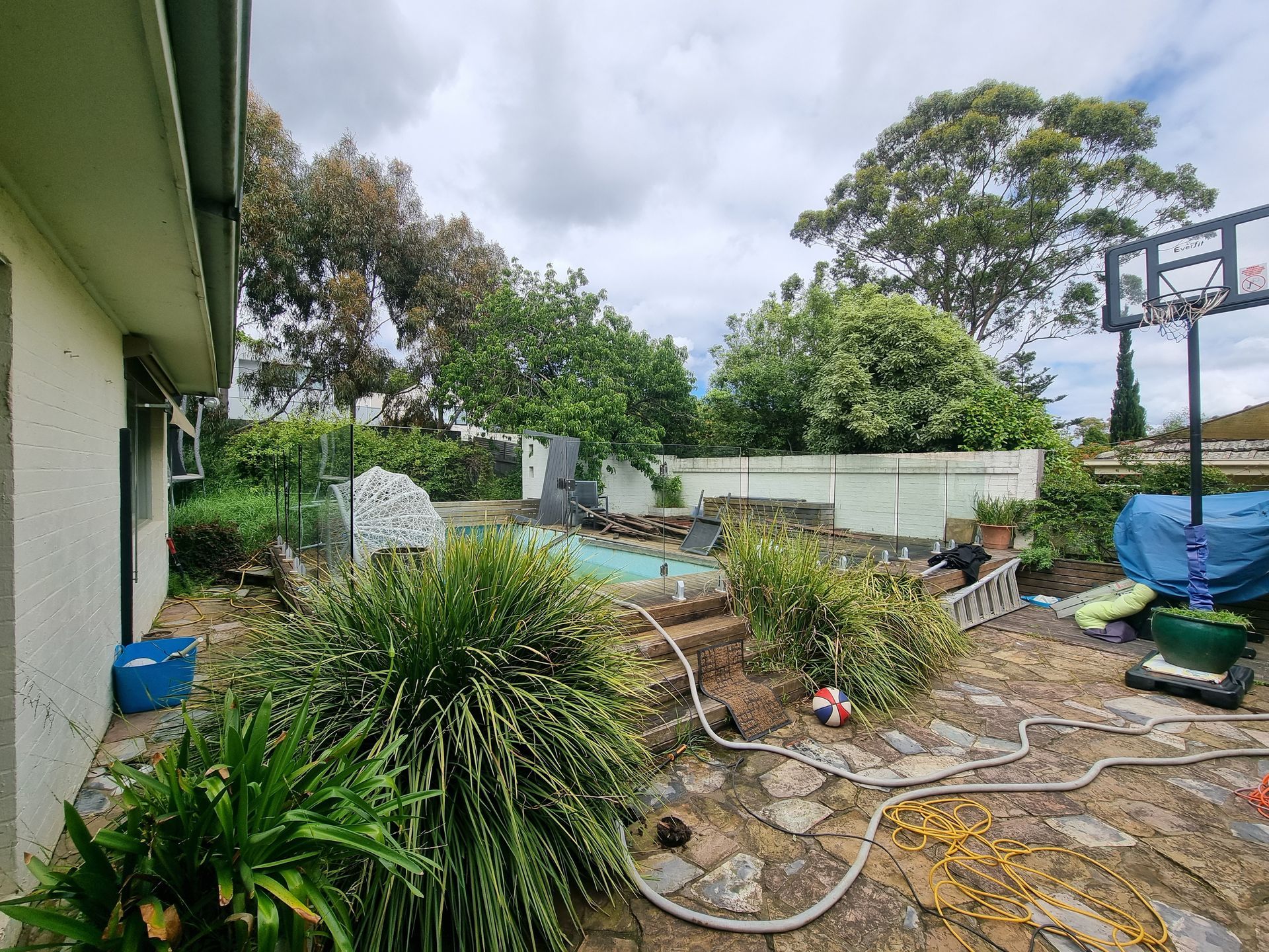 A Backyard With a Swimming Pool, Stone Patio, Basketball Hoop — All Over Pool Removals in Templestowe, VIC