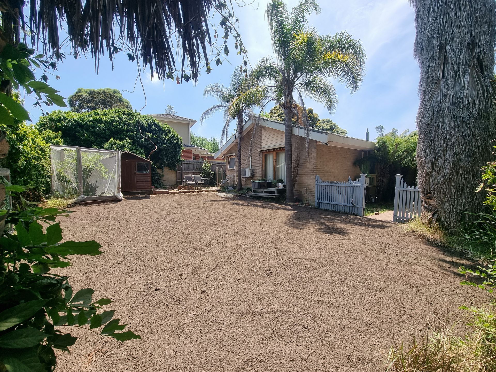 A Yard With Brown Dirt, a Palm Tree, and a Small Brick House — All Over Pool Removals in Templestowe, VIC