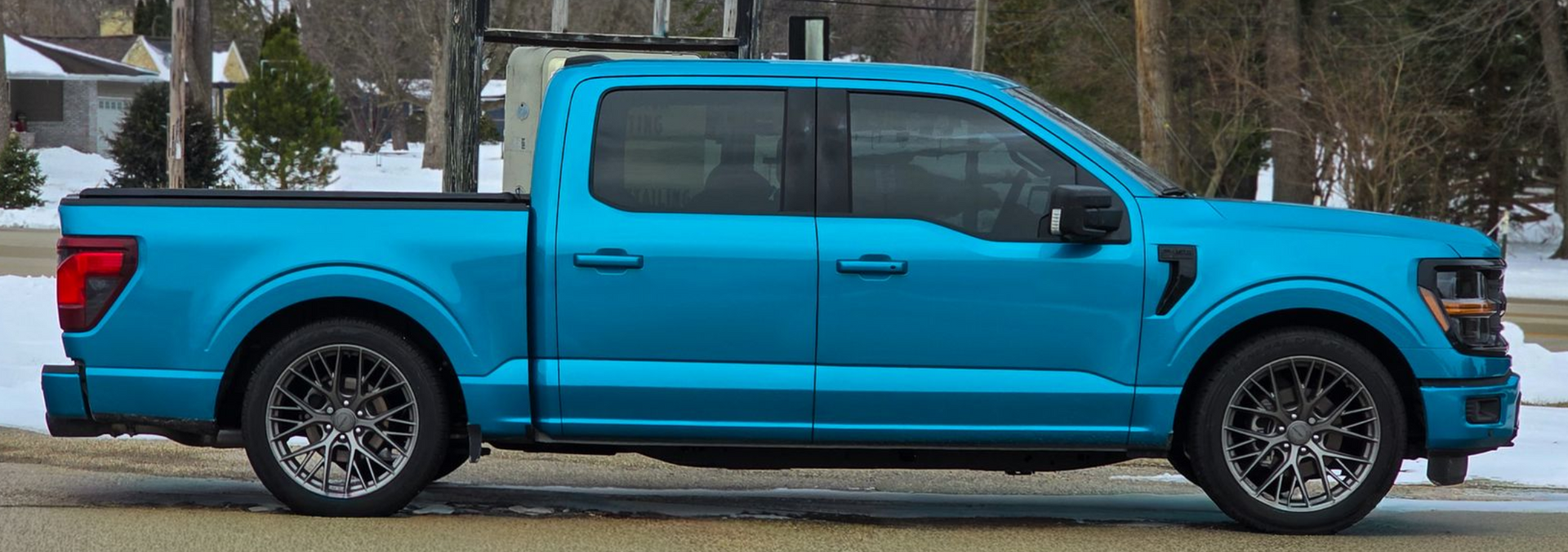 Bright blue Ford F-150 crew cab pickup truck parked outdoors on a snowy day.