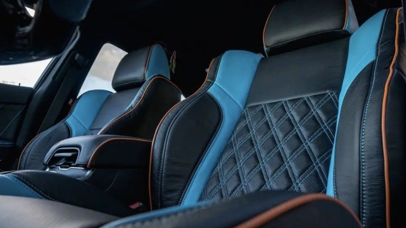 Car interior with black and blue bucket seats featuring diamond-pattern stitching and orange piping accents.