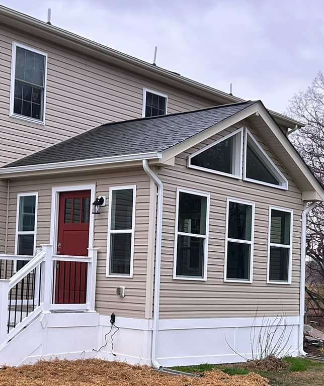 Small beige house entry with red door, white trim, and front steps under a gabled porch