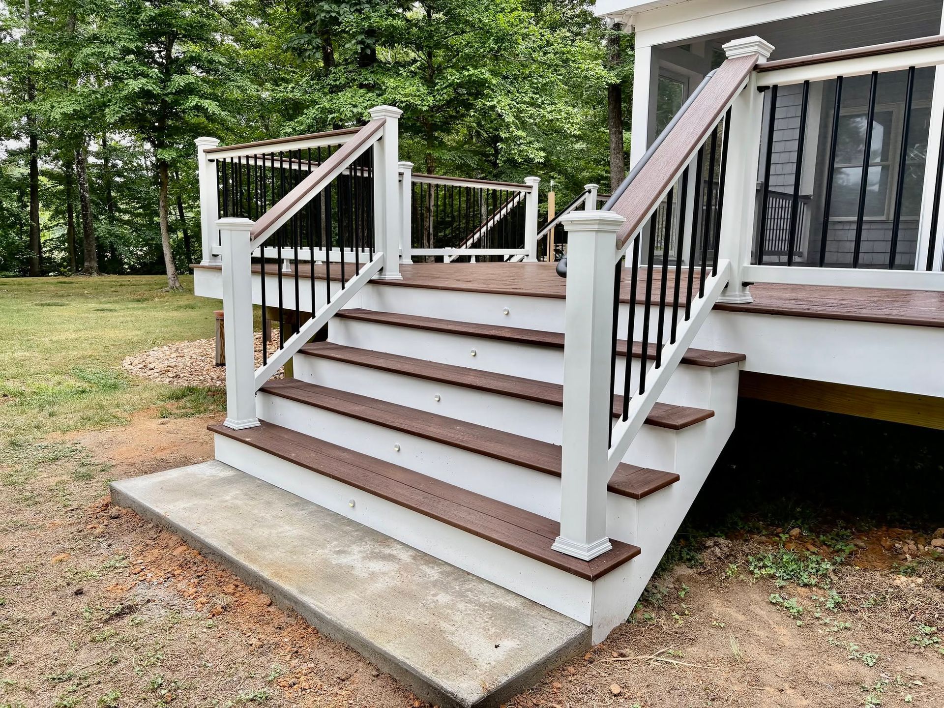 White wooden porch steps with railings leading to a house entrance from a concrete landing.