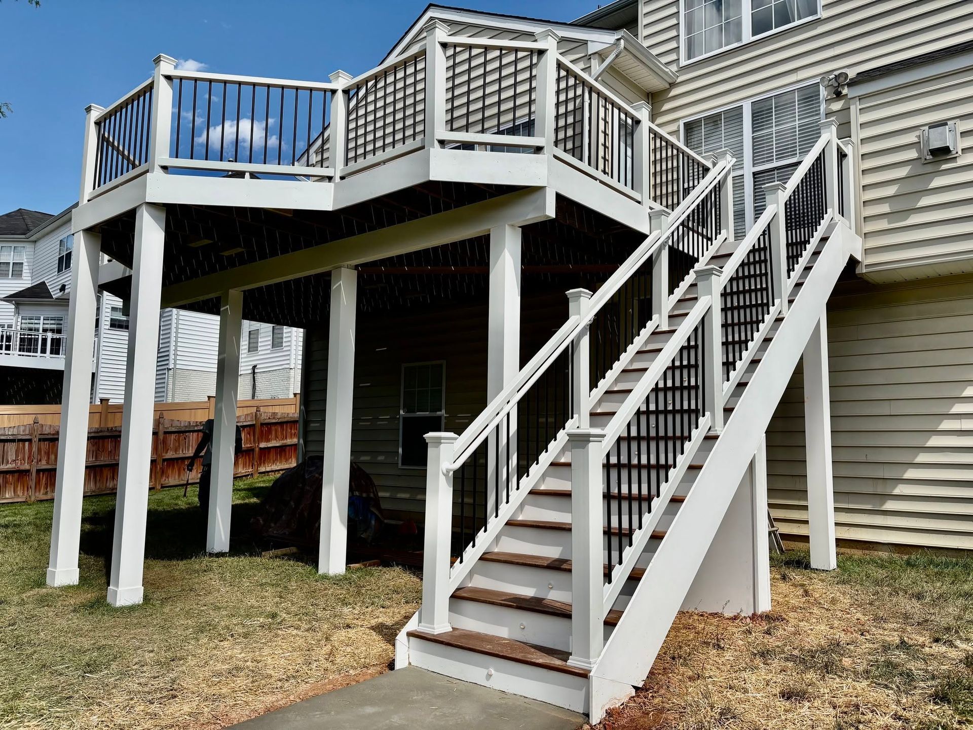 Raised wooden deck with white stairs and railings beside a house
