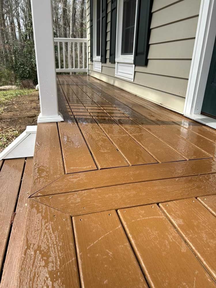 Wet orange-painted porch floor with white columns and beige house siding beside a walkway