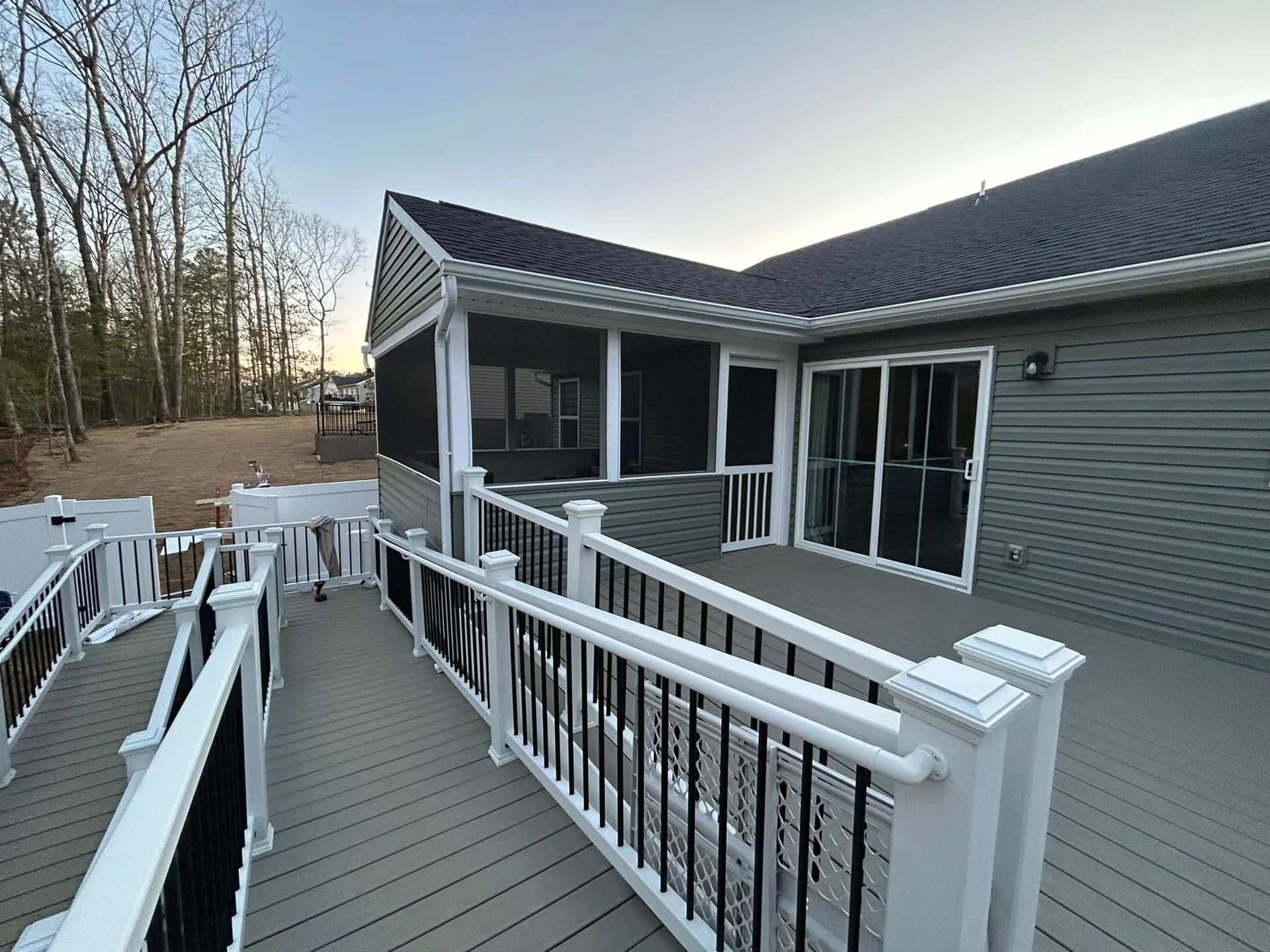 White deck ramp with railing beside a gray house and sliding glass doors outdoors