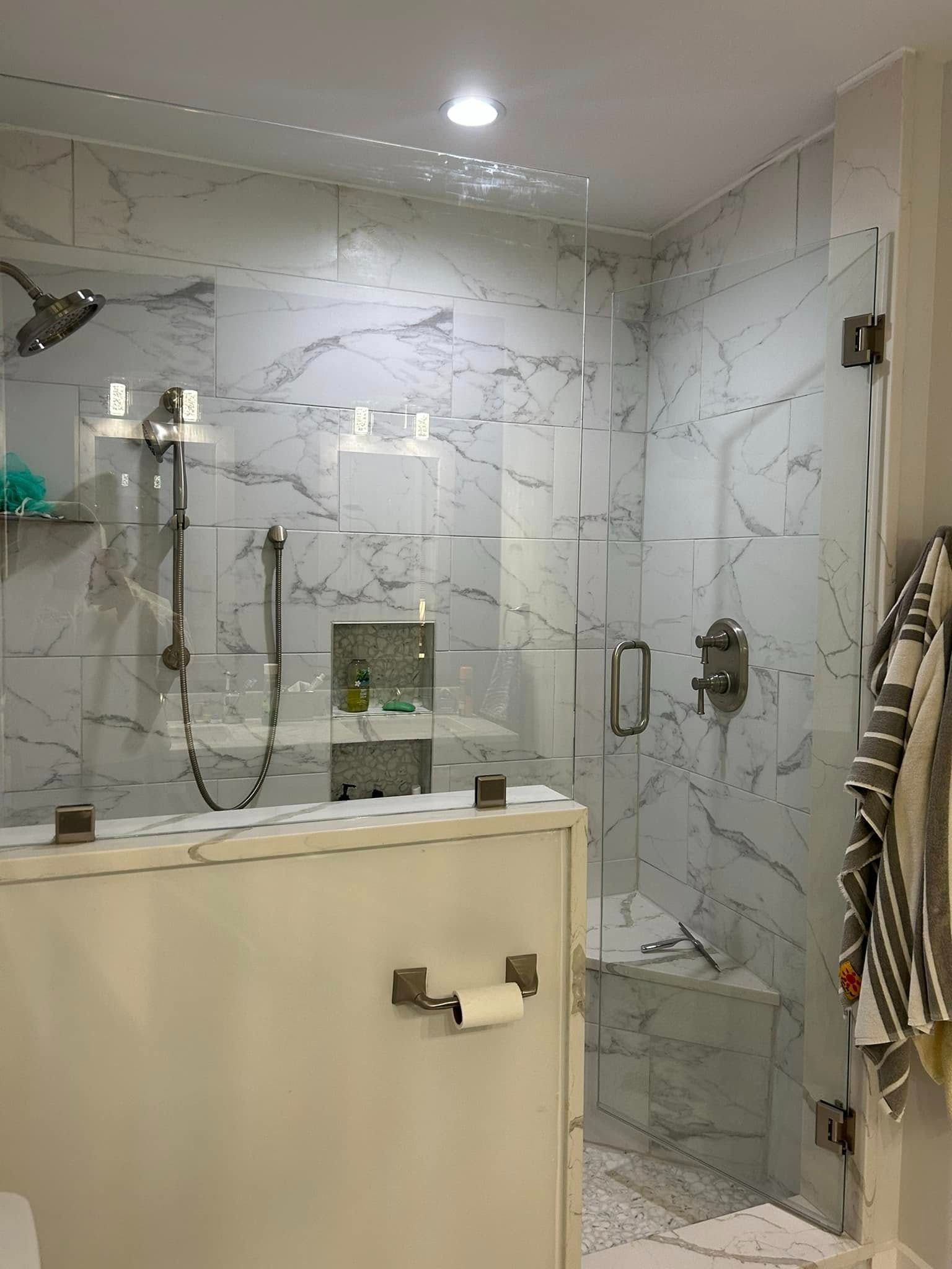 Modern bathroom with glass shower, marble tile, and beige vanity divider