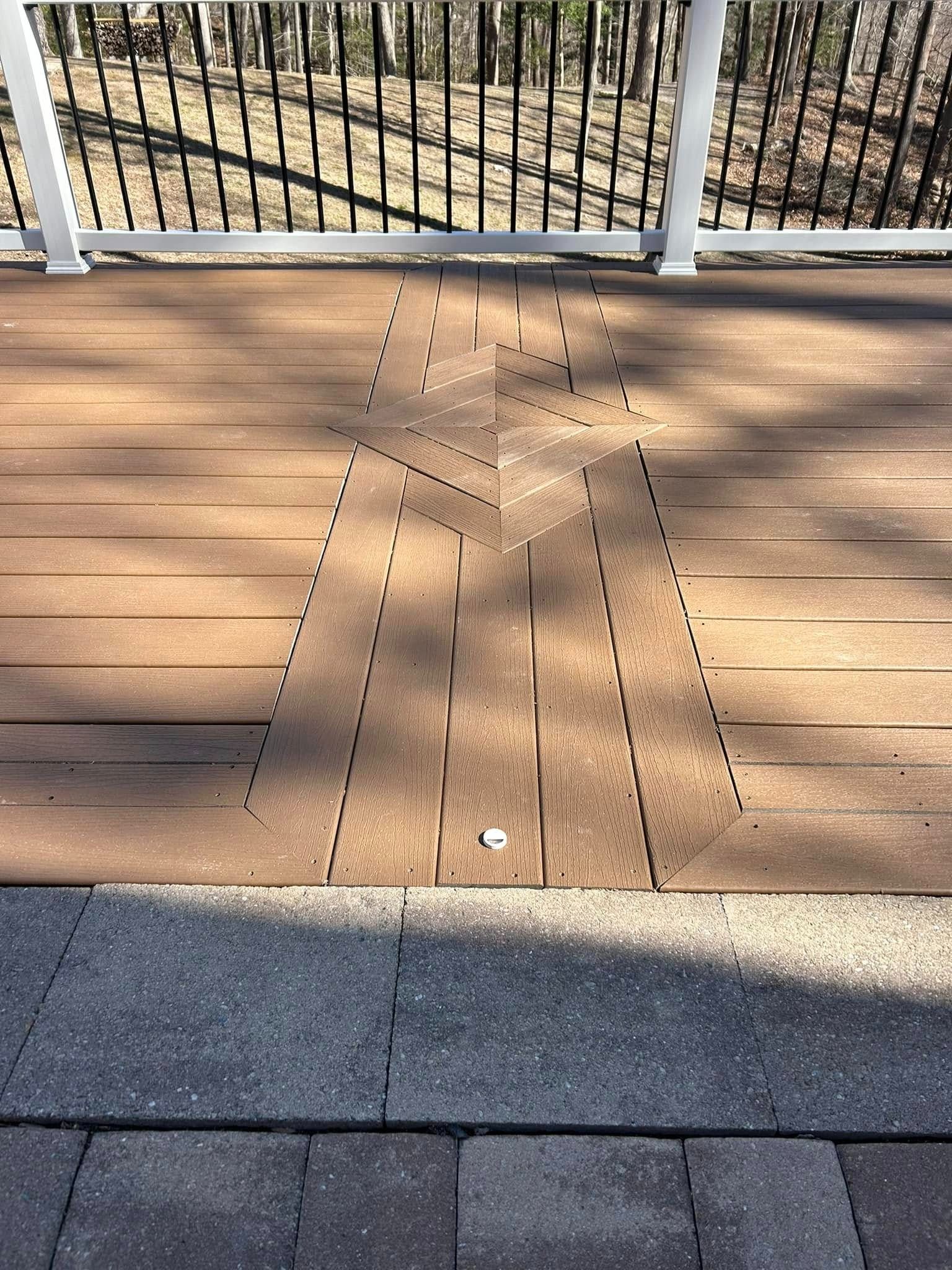 Dotted guide path on a wooden deck leading to a metal gate, with sidewalk in the foreground.