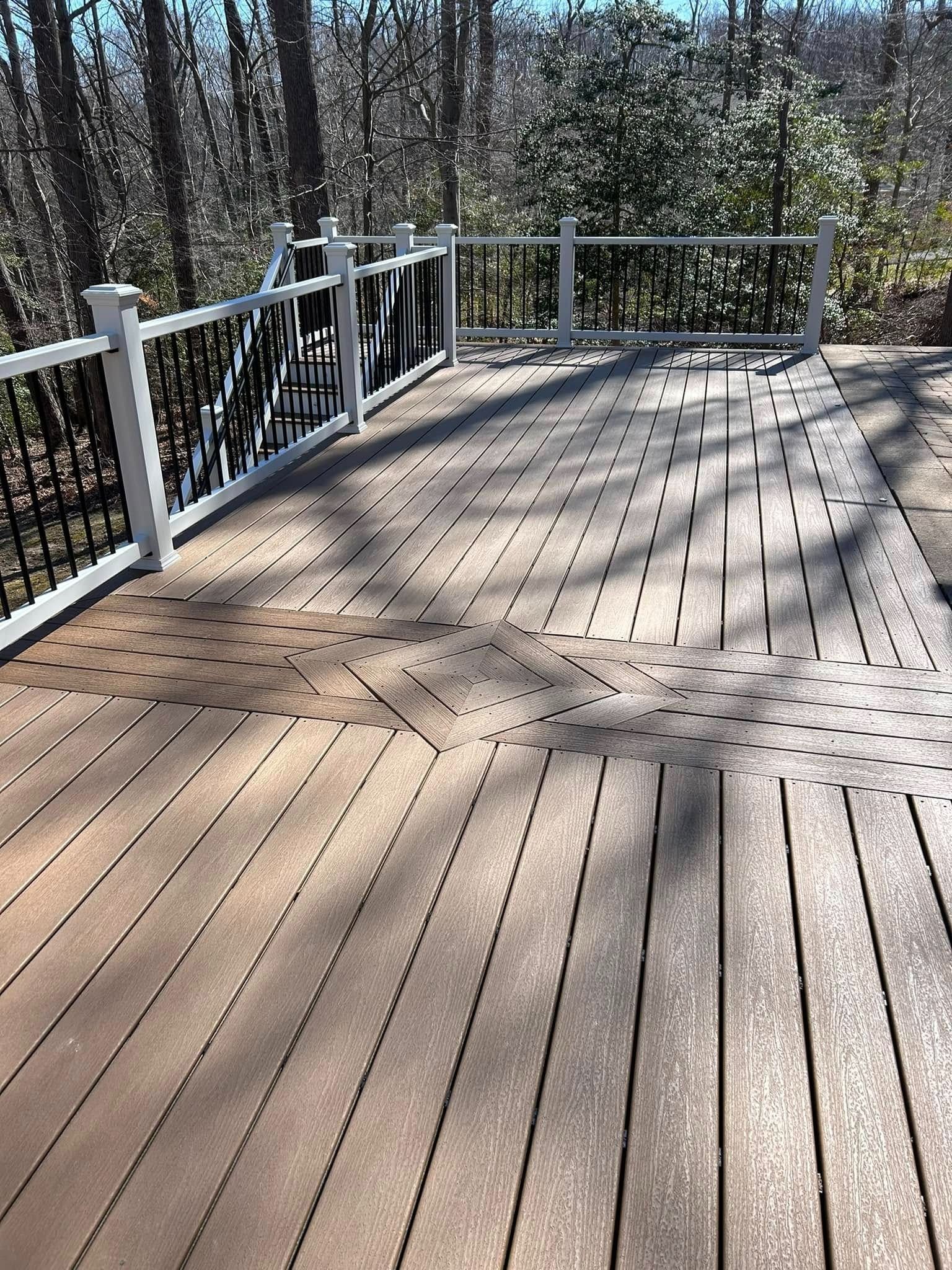 Wooden deck with white railings overlooking a wooded area in sunlight