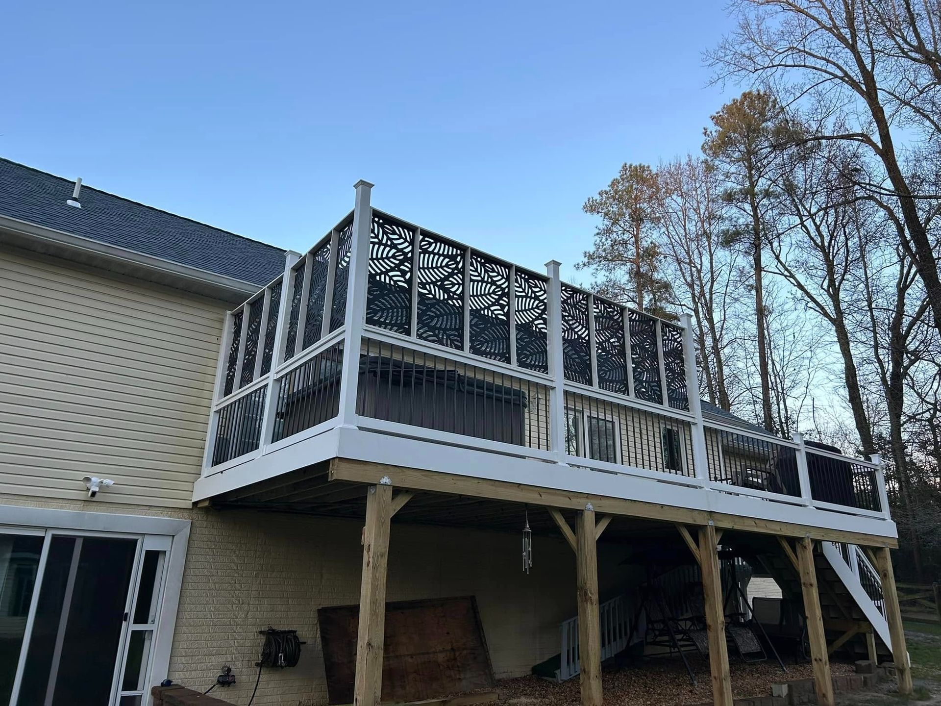 Elevated wooden deck with white railing under construction beside a beige house