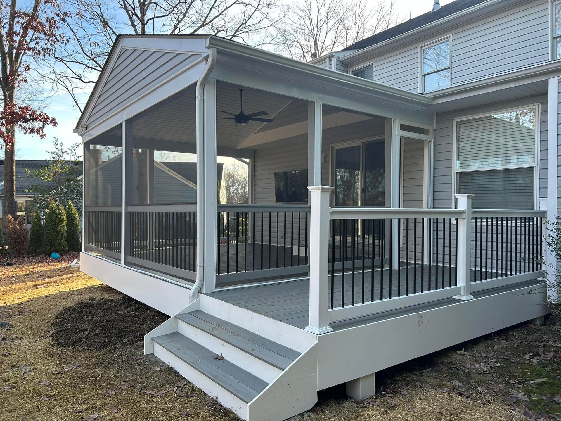 Covered porch with black railings and white steps on a gray house