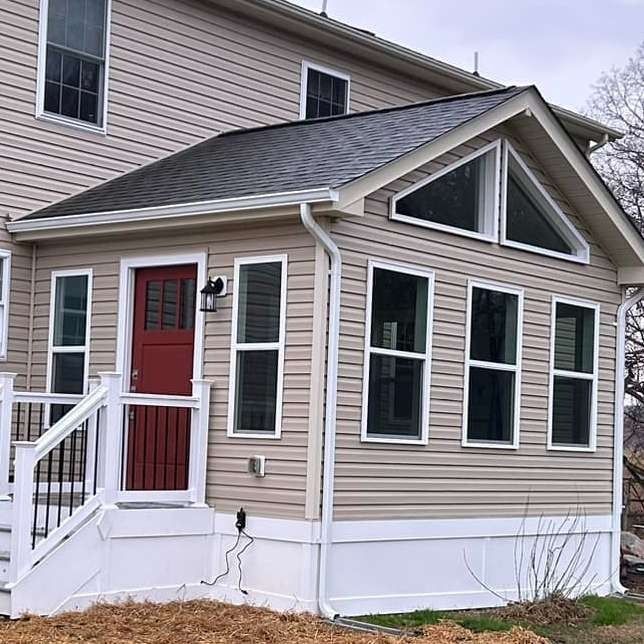 Red front door on a beige house with white trim and a small porch with steps and railing