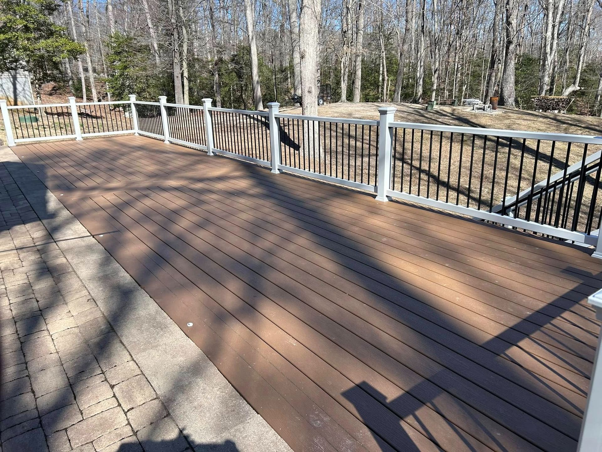 Wooden boardwalk with white railings winding through a wooded park in sunlight