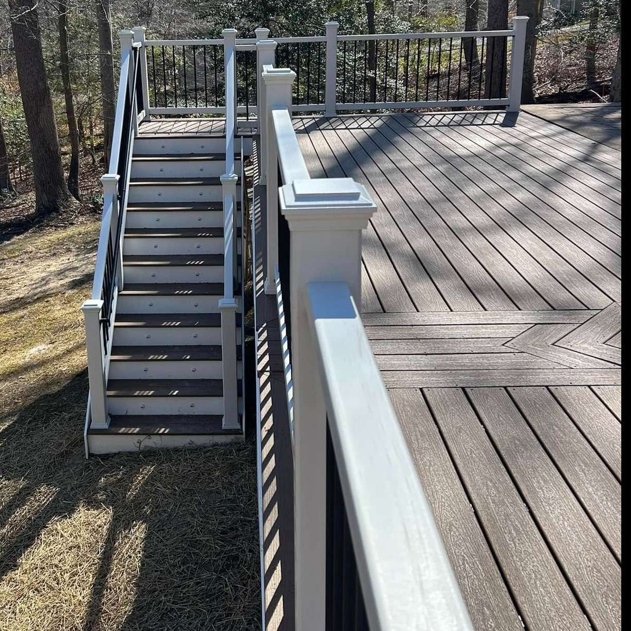 Wooden deck with stairs and white railing in a sunny outdoor setting