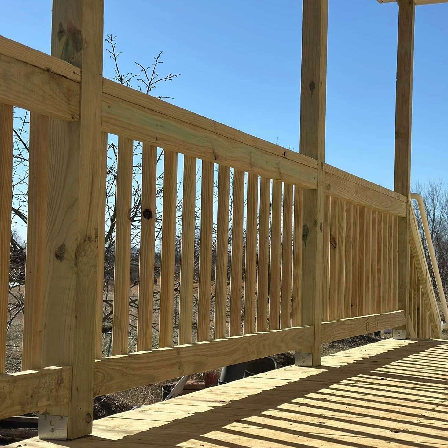 Wooden railing on a sunny outdoor deck with striped shadows and blue sky