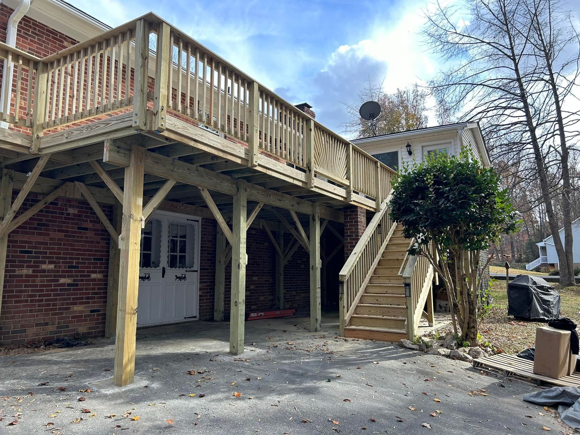 Backyard deck with wooden stairs, brick house, and leafless trees in winter.
