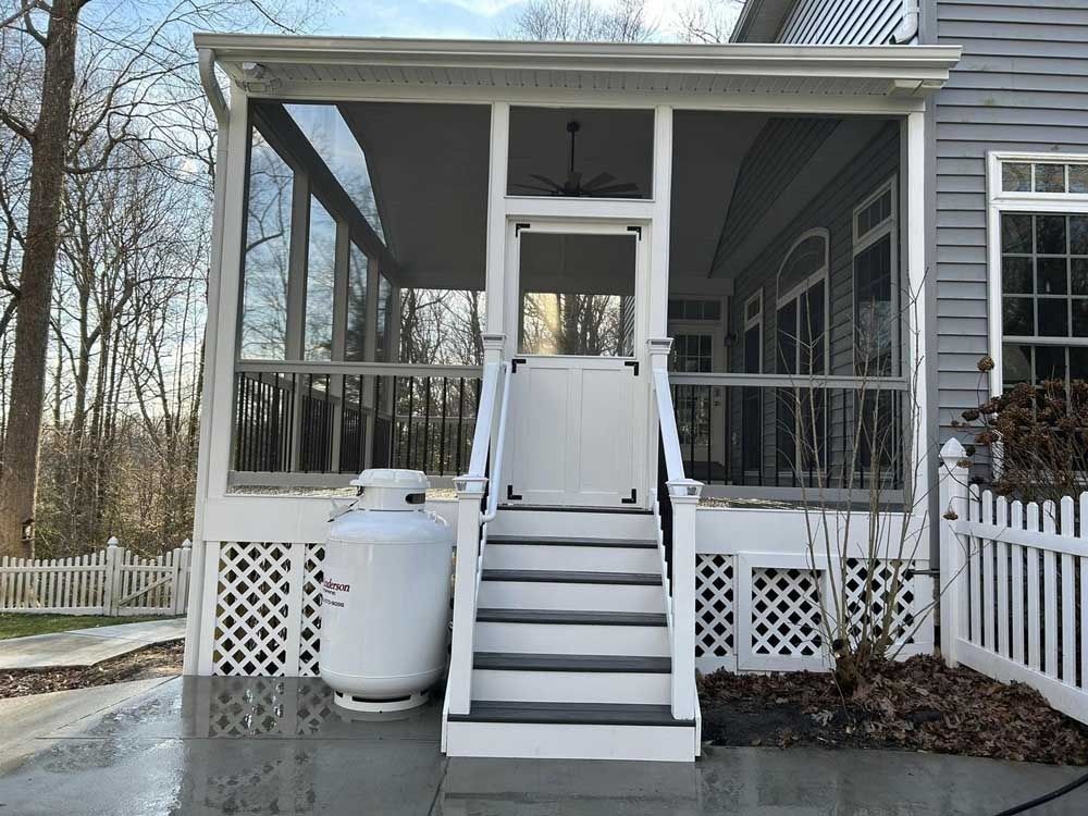 House porch with an exterior staircase, snow on the ground, and propane tanks beside the steps